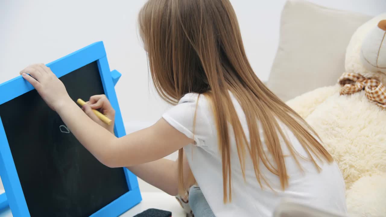 小女孩在家里的4k视频白板上画画。视频下载