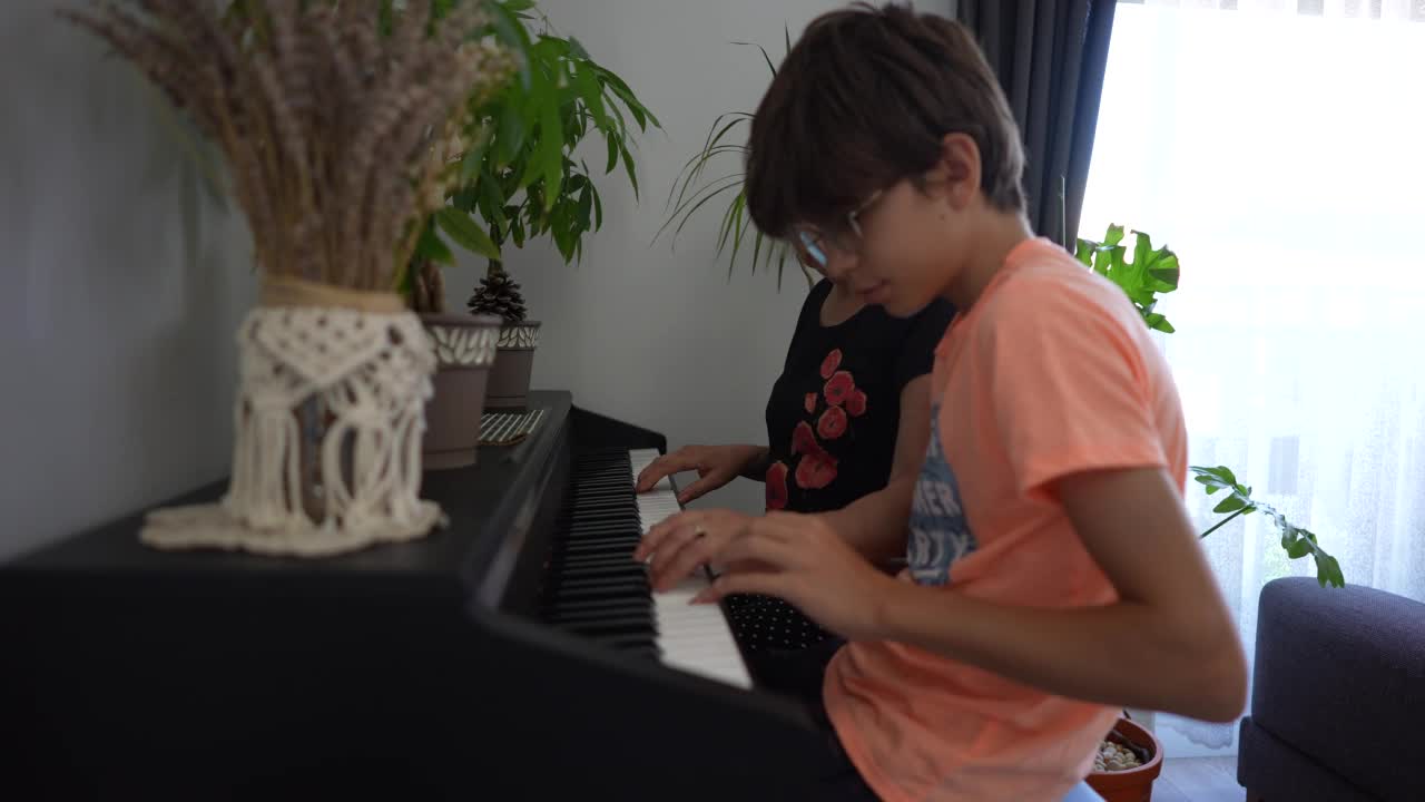一个十几岁的男孩和他的祖母一起学习弹钢琴视频素材