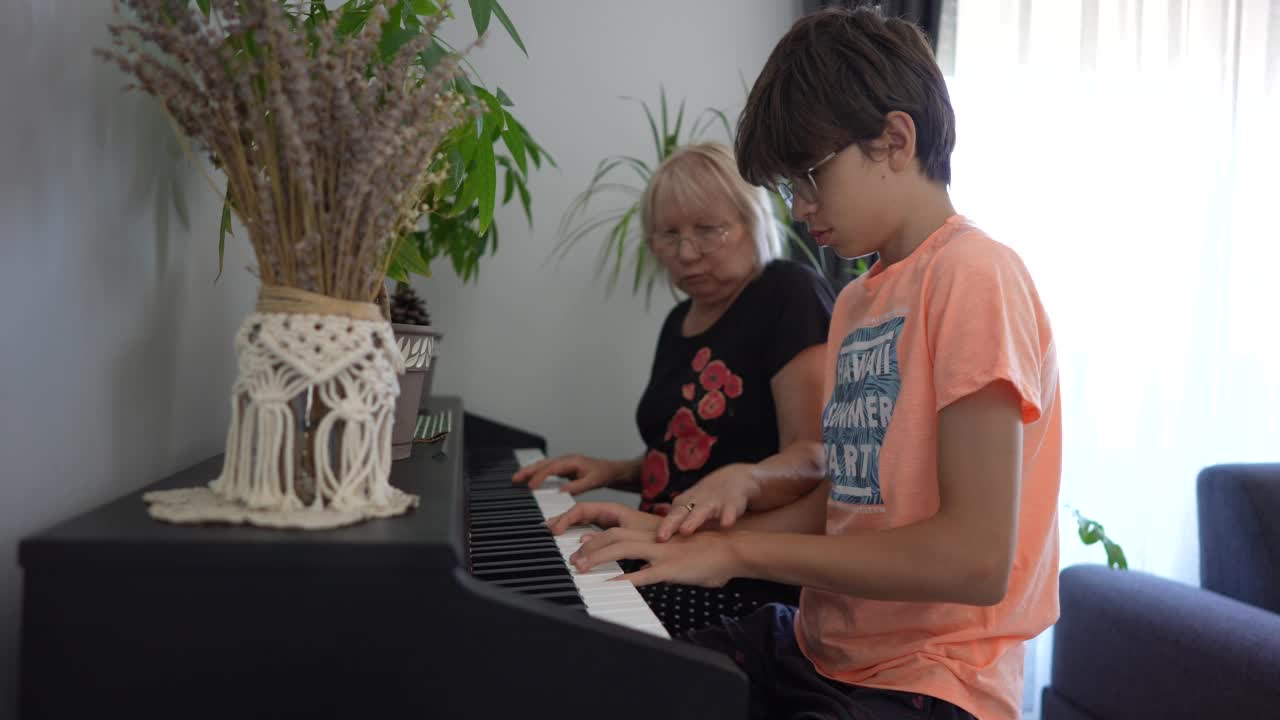 一个十几岁的男孩和他的祖母一起学习弹钢琴视频素材