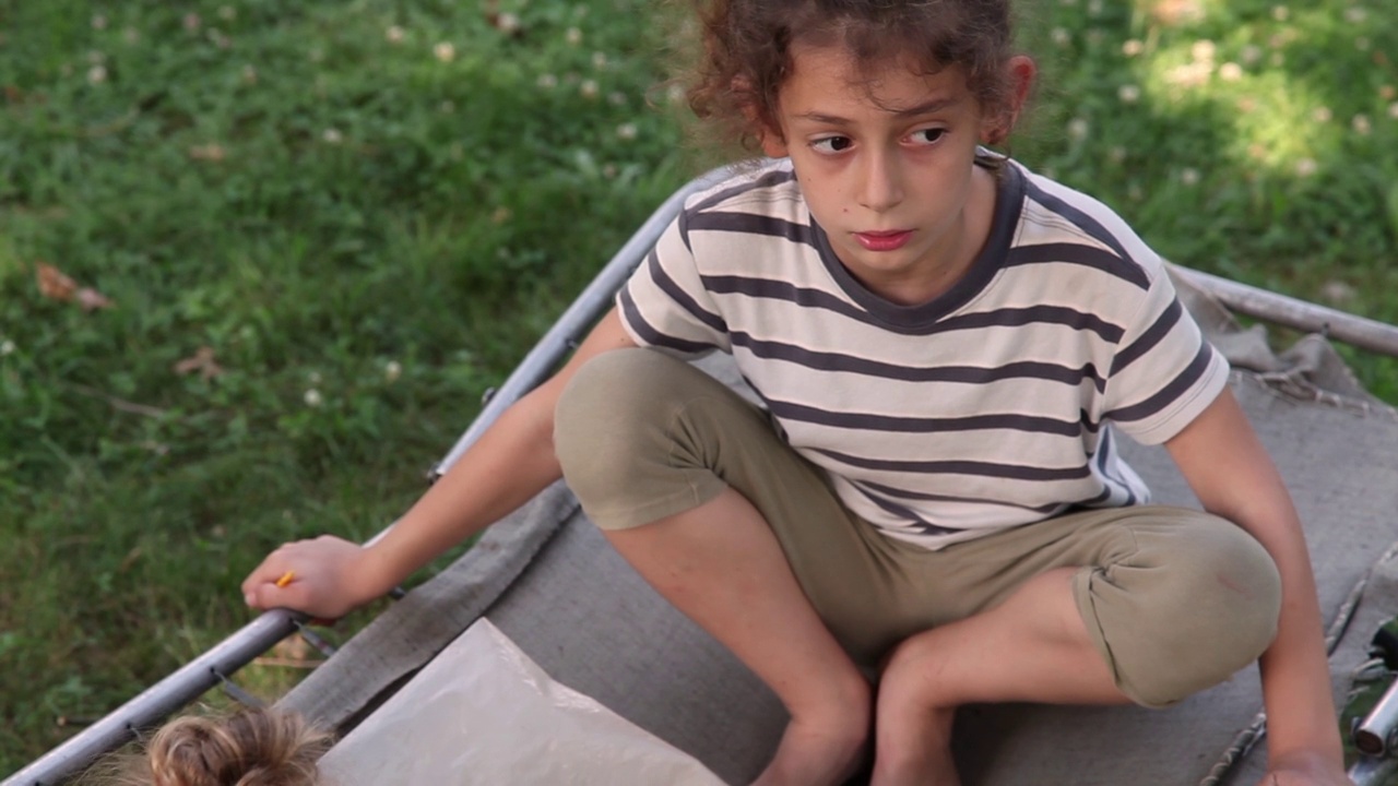 困惑的小女孩坐在公园的露营床上视频素材