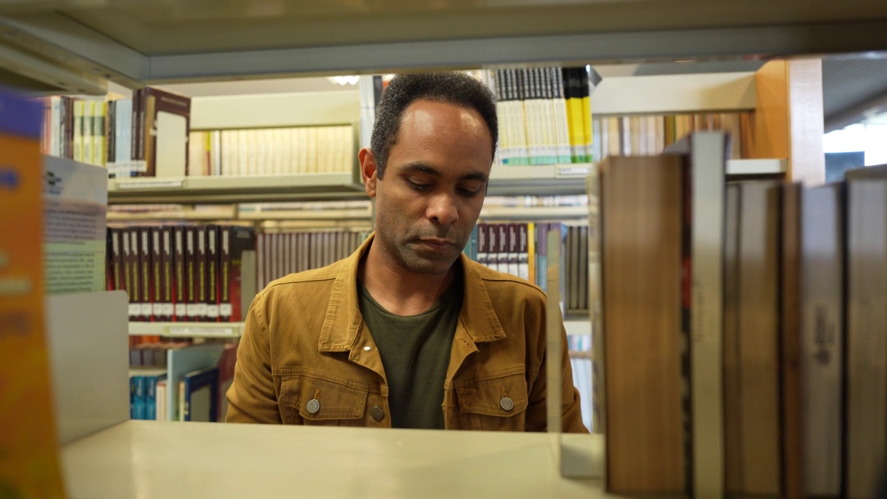 一名男子从图书馆的书架上取书视频素材
