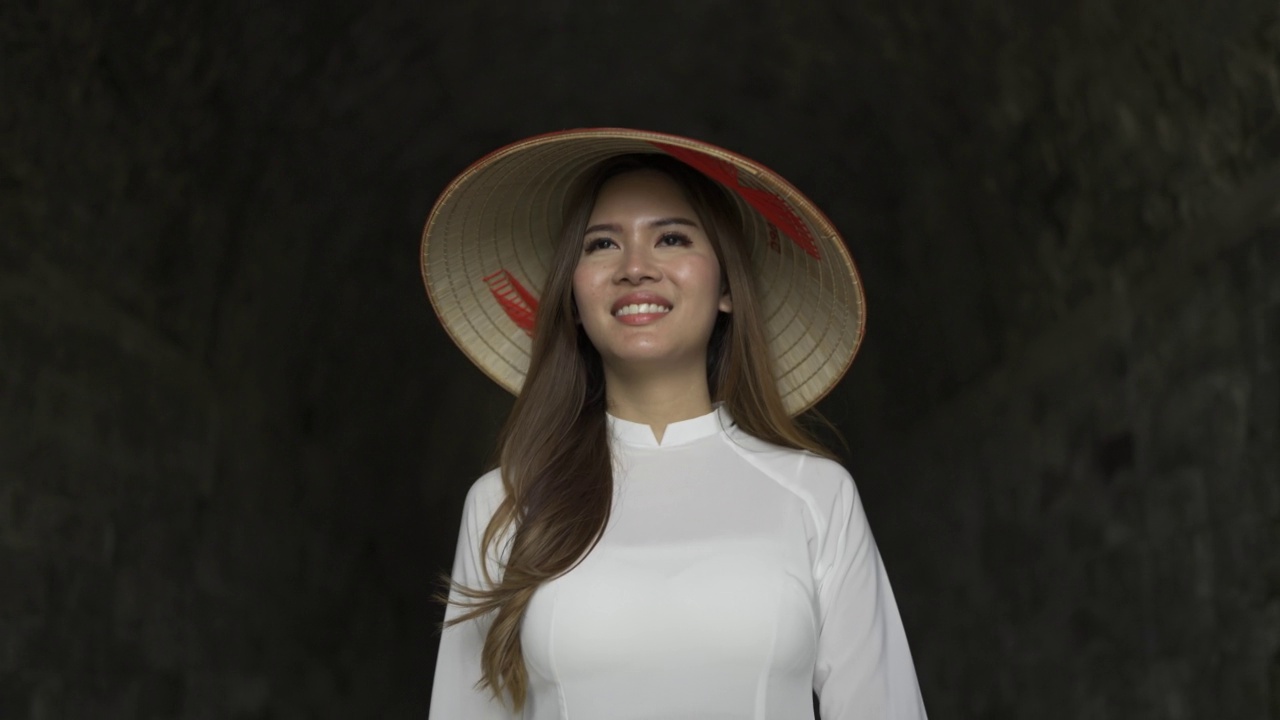 4K越南妇女穿着传统服装，戴着亚洲风格的锥形帽子走在隧道里视频下载