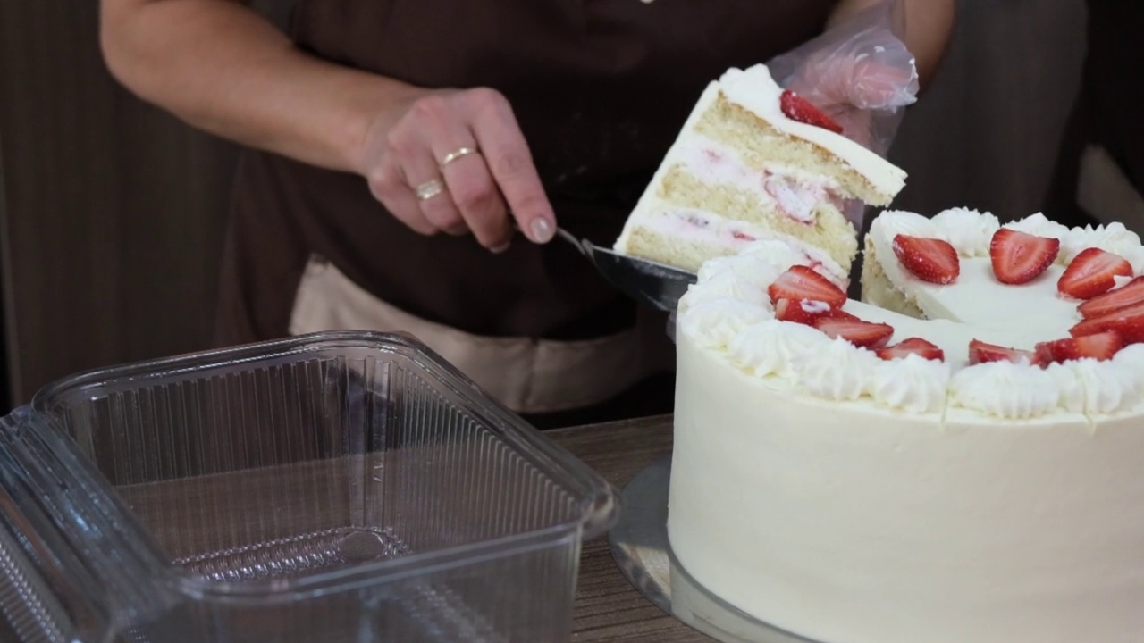 女性的手把诱人的蛋糕放在塑料盒子里给顾客。视频下载