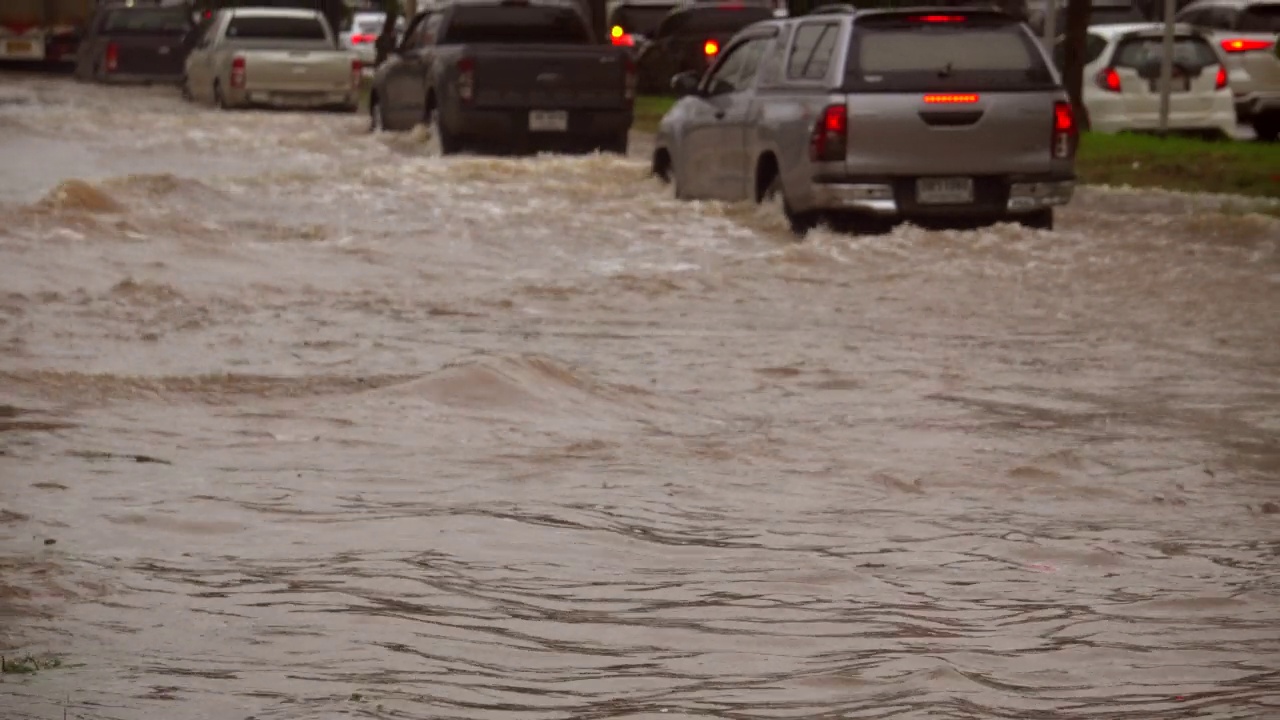 暴雨后行驶在被淹道路上的汽车。视频素材