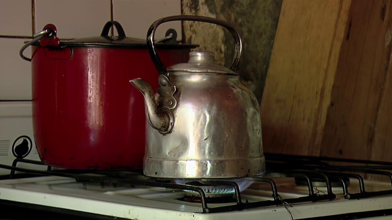 在老式厨房的旧茶壶里加热水。关闭了。视频素材