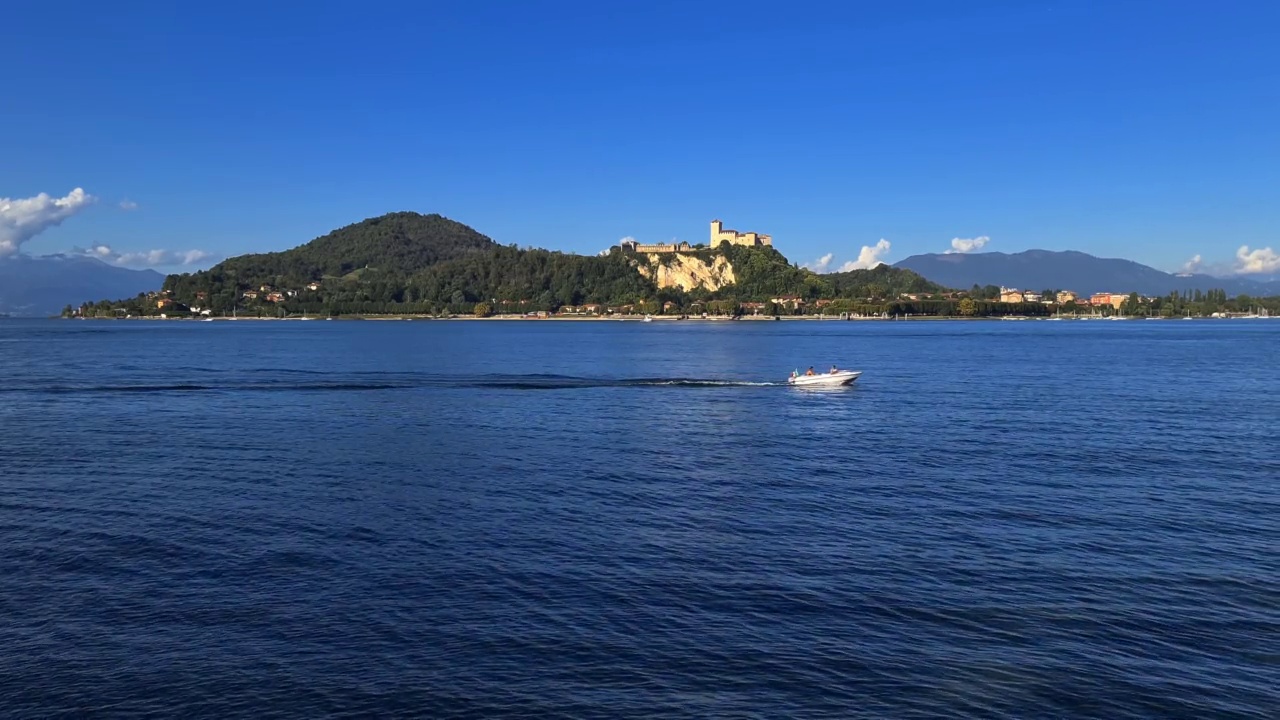 小汽艇在意大利马乔雷湖平静的湖水中航行，背景是安格拉城堡视频素材
