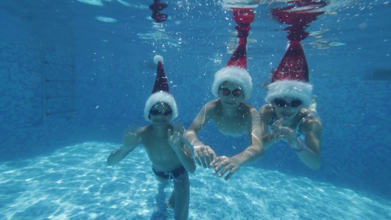 夏天的圣诞节，孩子们在游泳池里游泳视频素材