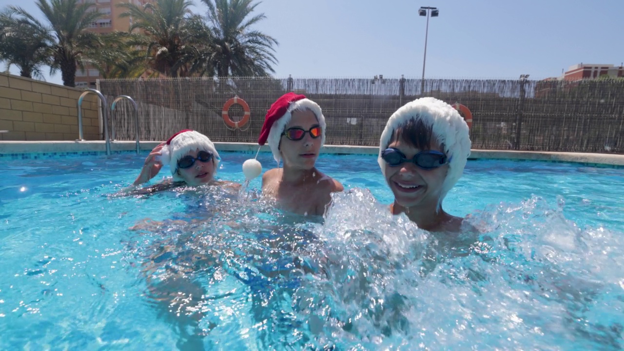 夏天的圣诞节，十几岁的孩子们在游泳池里游泳视频素材
