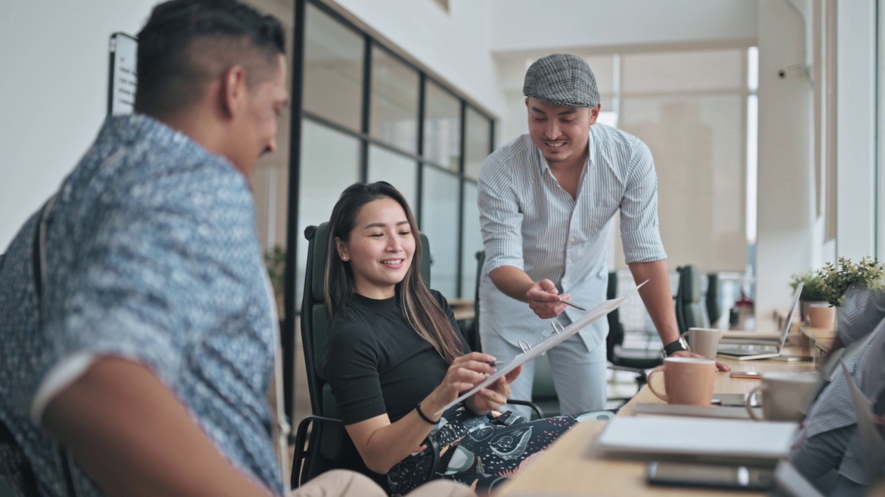 多元化亚裔印度白领坐在轮椅上与同事一起工作在创造性的办公室工作站视频素材