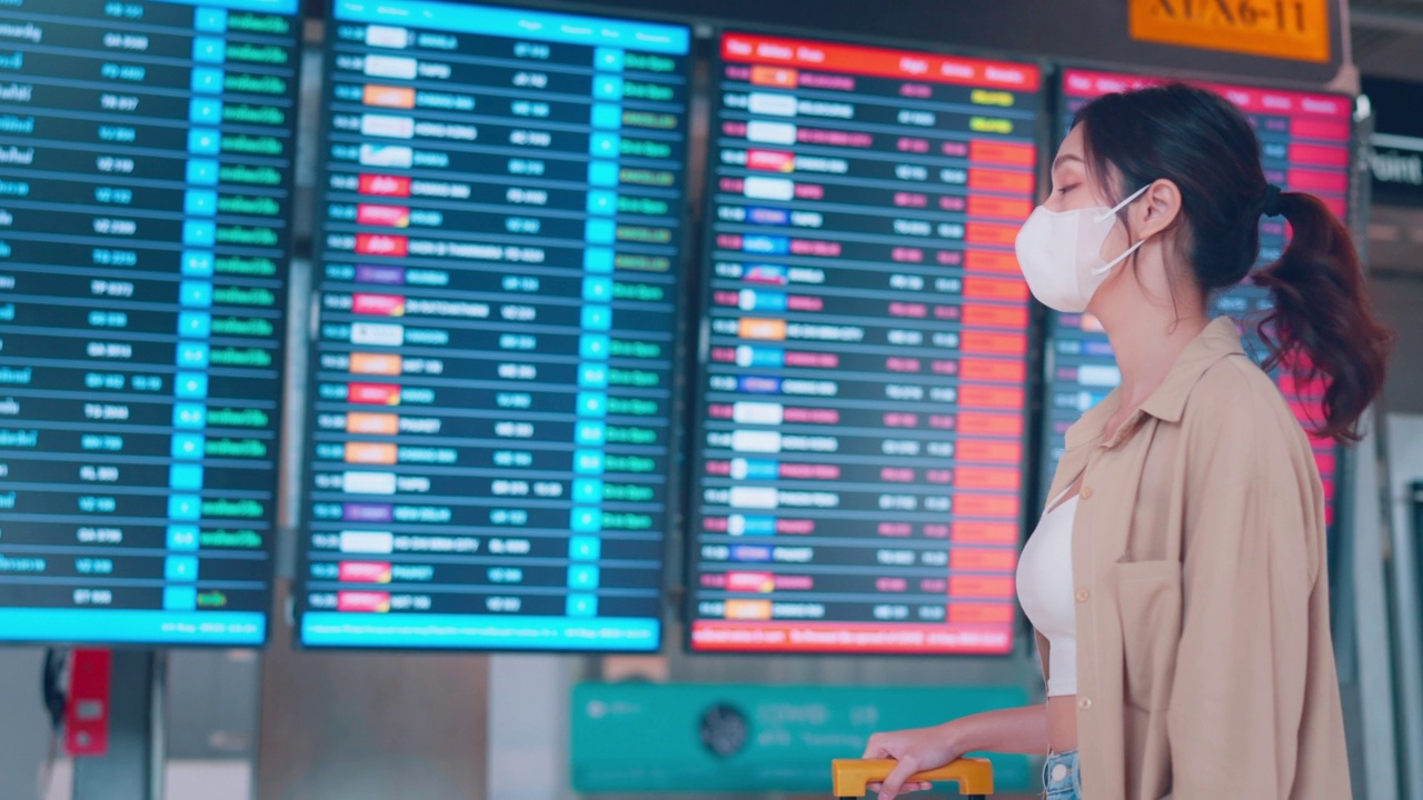 亚洲女旅客在机场候机楼查看航班时刻表。旅游旅程旅行概念视频素材