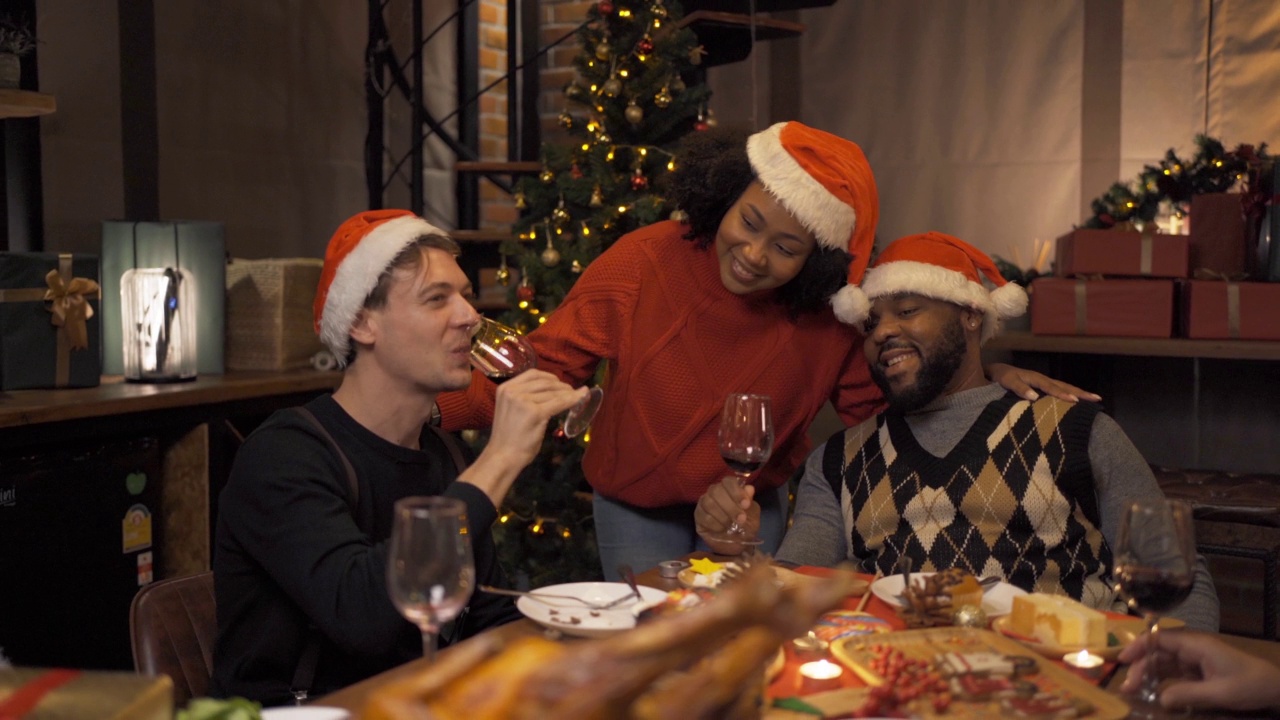 一个多民族的群体。白人和非裔美国黑人家庭的画像，妇女在圣诞夜的聚会上有一个庆祝晚餐在节日的家里或家里。人们的生活方式。视频下载