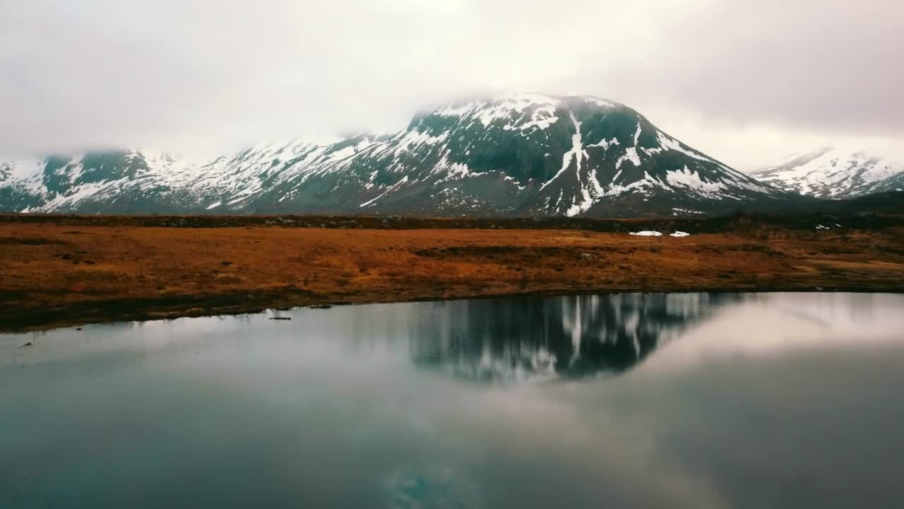 鸟瞰宁静的雪山美景，无人机飞越起伏的湖面——挪威特罗姆瑟视频素材