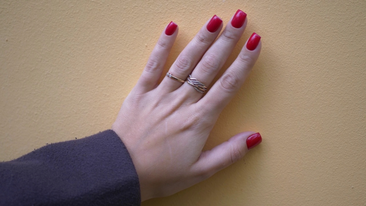 女人的手掌，涂着红色的指甲，黄色的表面镶着金戒指。视频下载