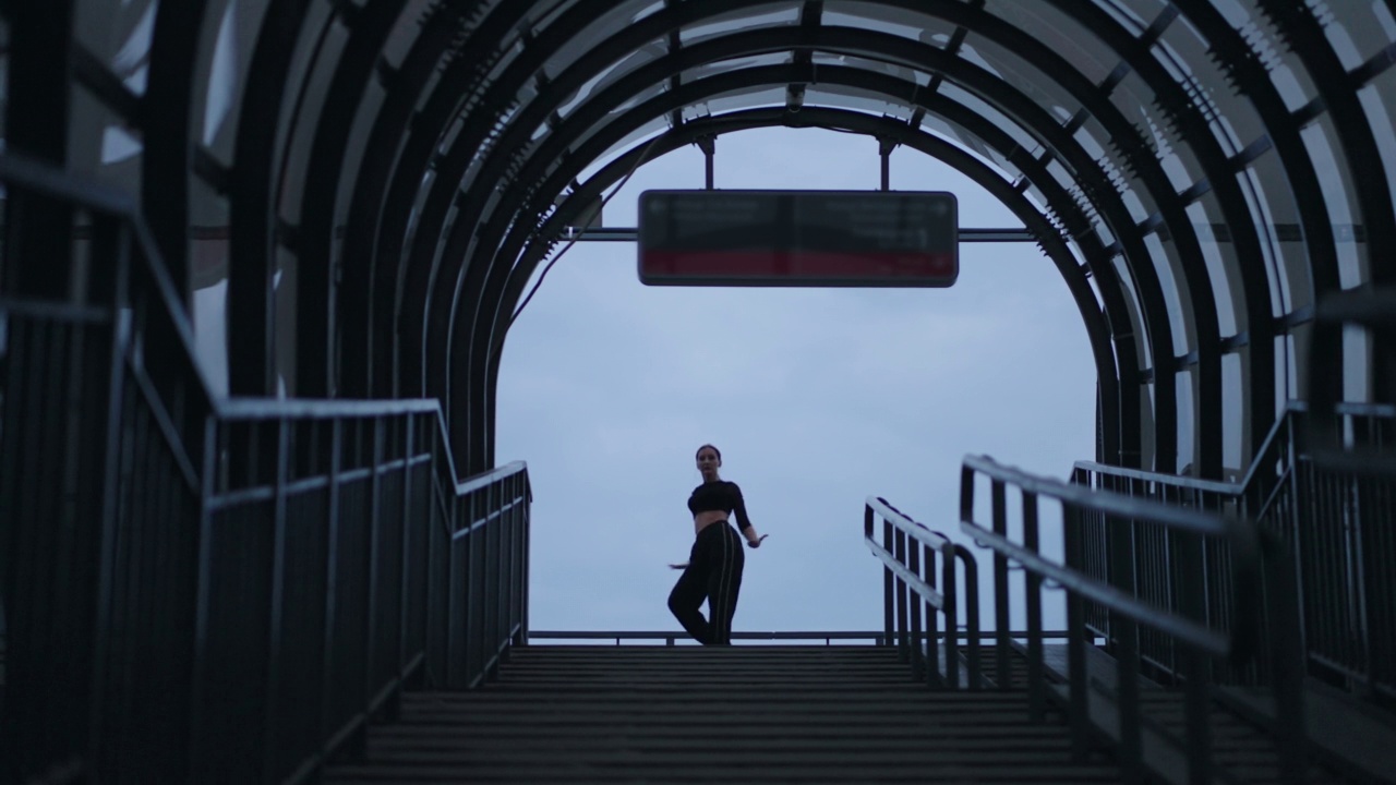 优美的舞女在大城市人行天桥的走廊上跳着现代街舞视频素材