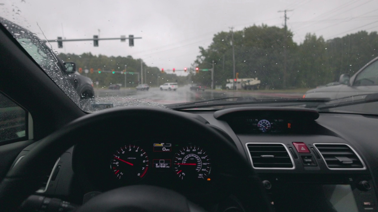 在恶劣天气下驾驶红绿灯繁忙的十字路口-下雨视频素材