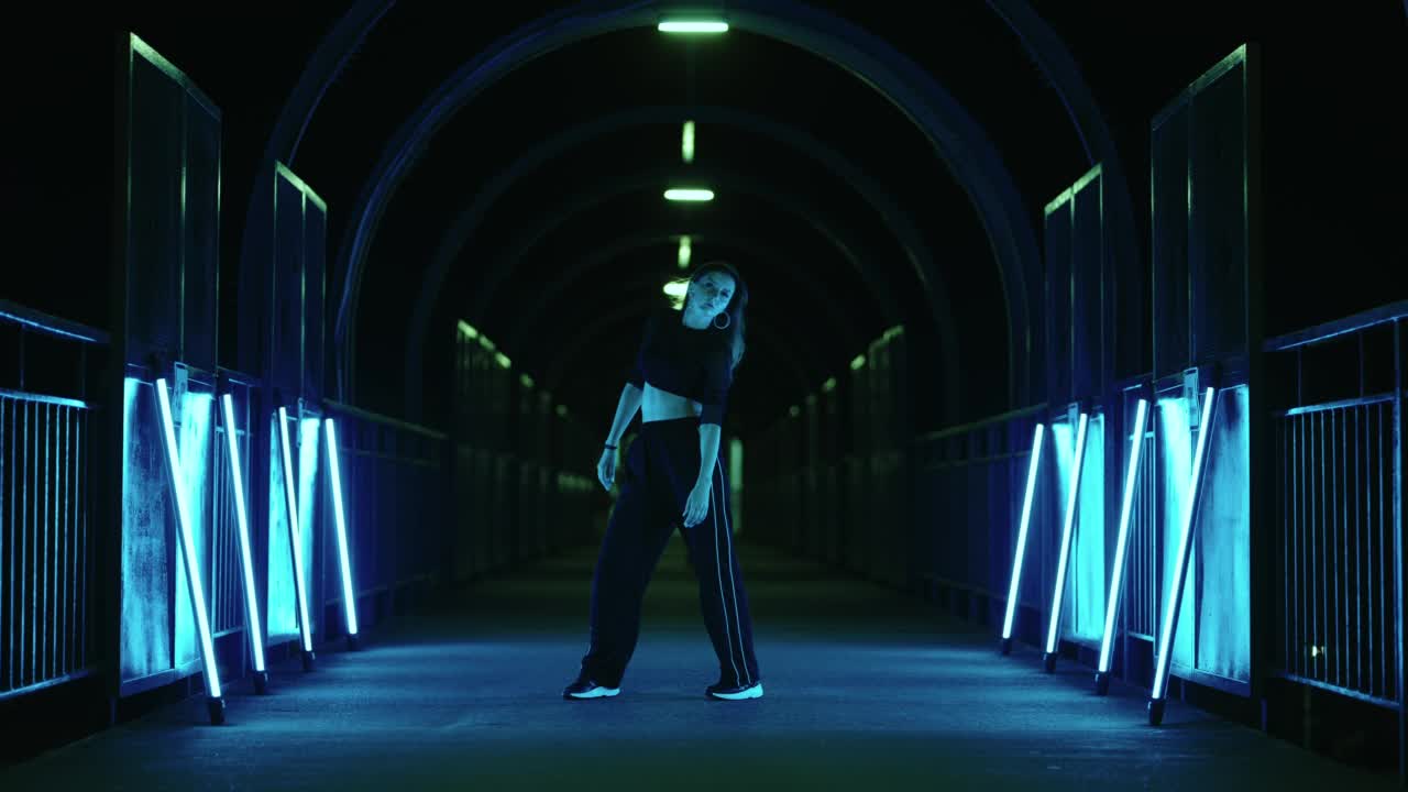 性感苗条的女人正在跳现代街舞与神秘的蓝色灯光的黑暗隧道视频素材