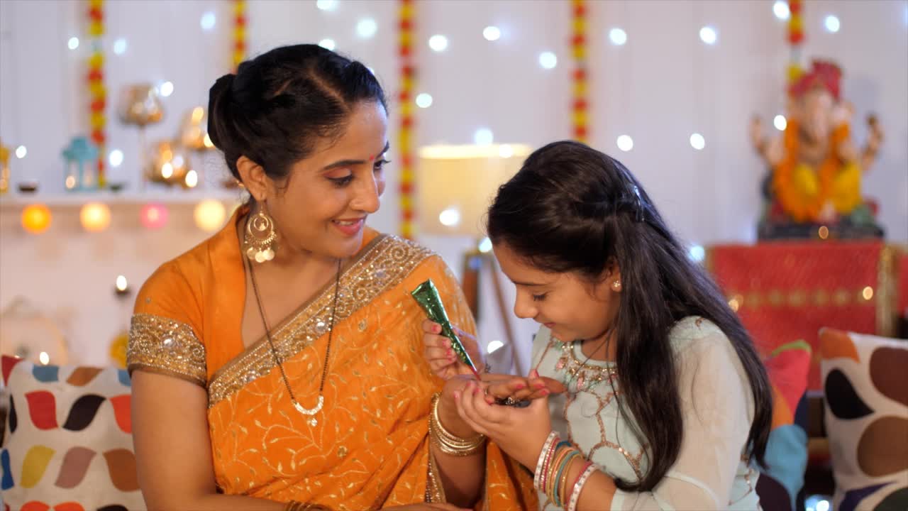 一个穿着民族服饰的印度女孩正在用排灯节庆祝用的印度纱丽装饰她母亲的手视频素材