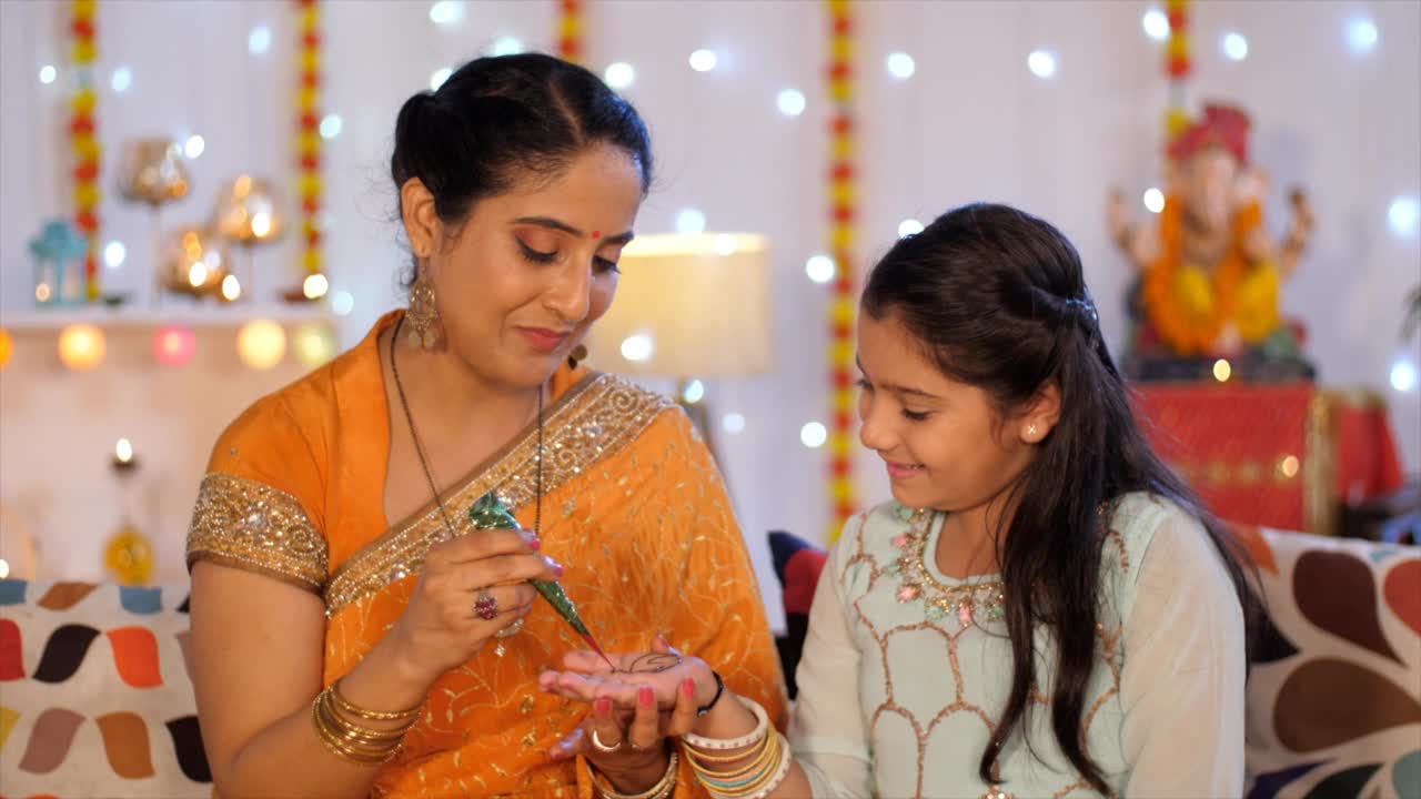 一位漂亮的印度女士在她的小女孩的手上用指甲花/ Mehendi装饰——排灯节庆典，印度文化视频素材