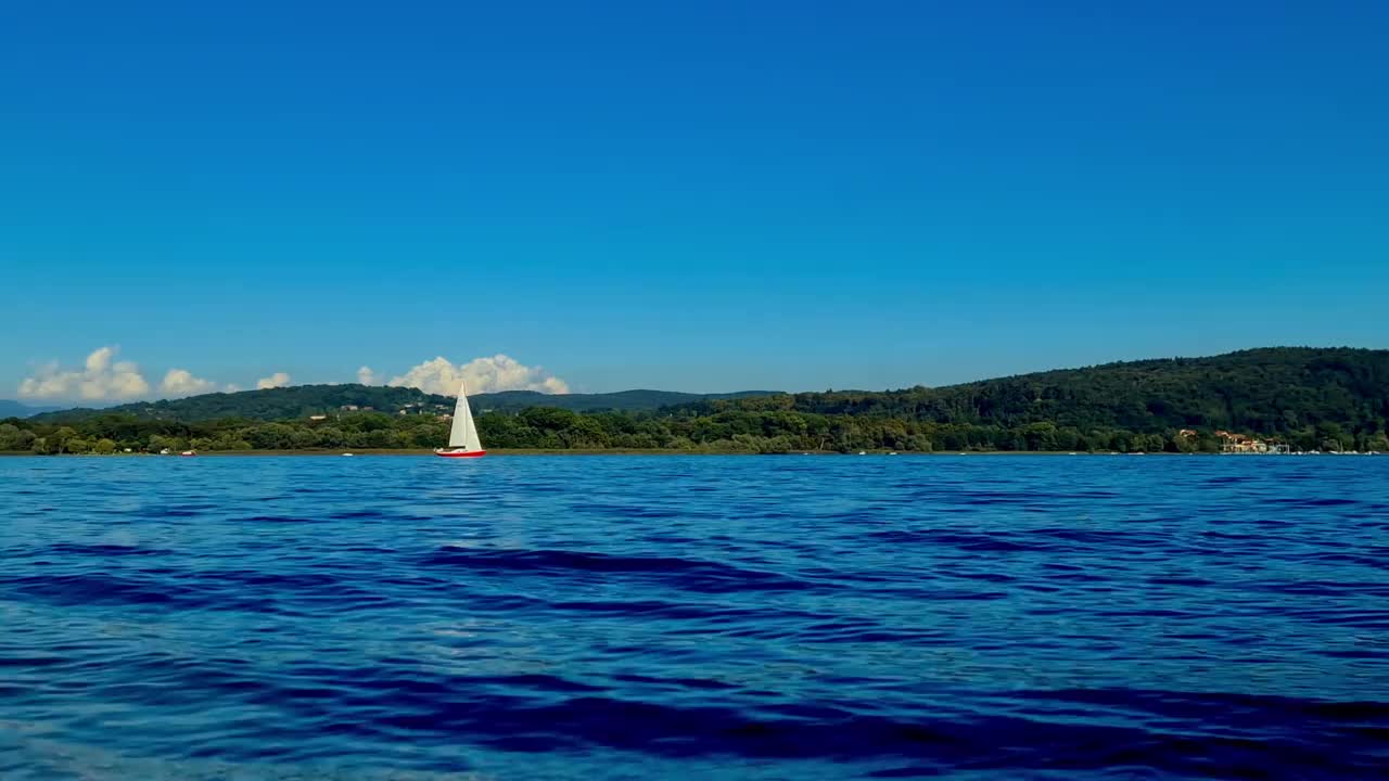意大利马焦雷湖平静开阔的湖面上航行的小船的低角度视角视频素材
