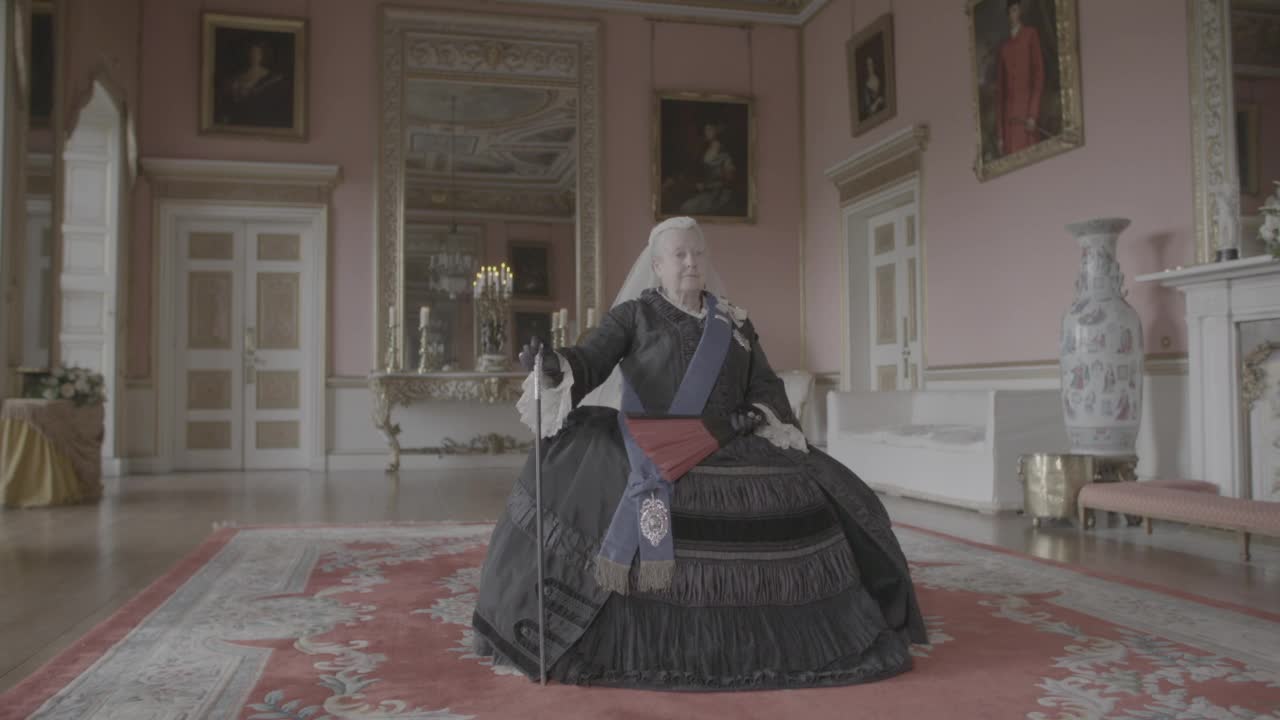 年长的维多利亚女王坐在大宫殿的房间里，拿着一把扇子和手杖——格鲁吉亚时代的再现视频素材