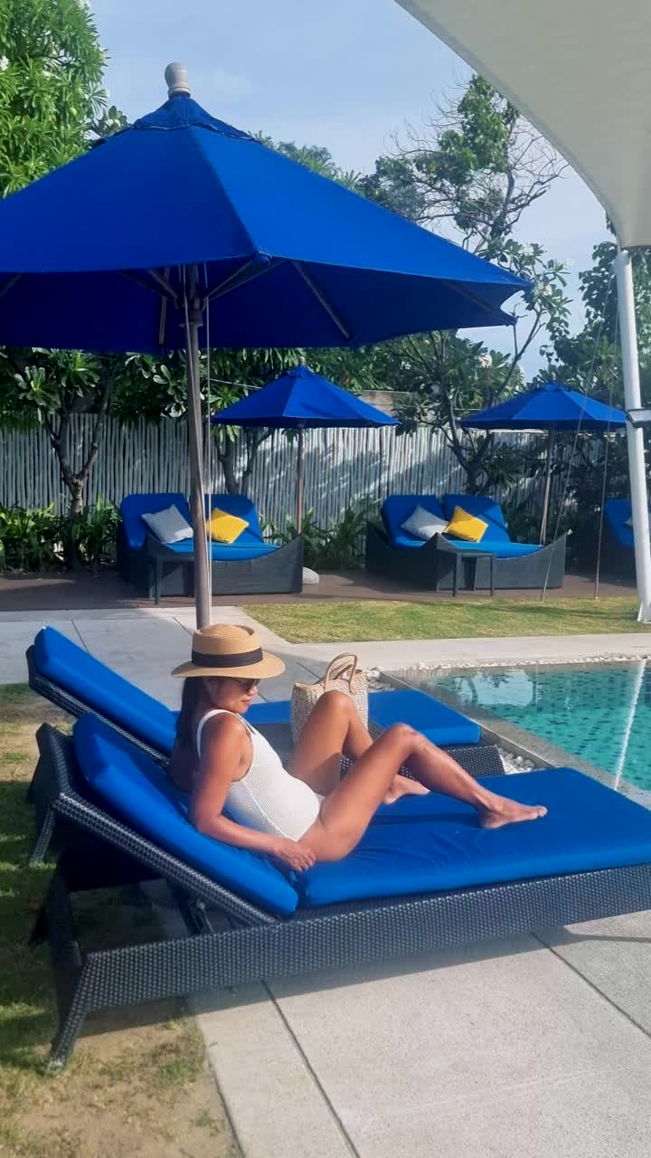 度假期间，女性在泳池边放松，在日光浴床上，亚洲女性望着大海视频下载