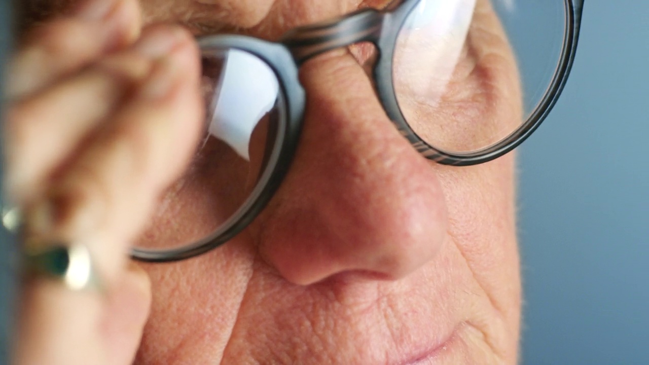 眼镜，视力和老年人尝试新眼镜，眼镜或眼镜的脸。放大微距，眼睛或视力的人在退休与处方镜片在蓝色背景视频下载