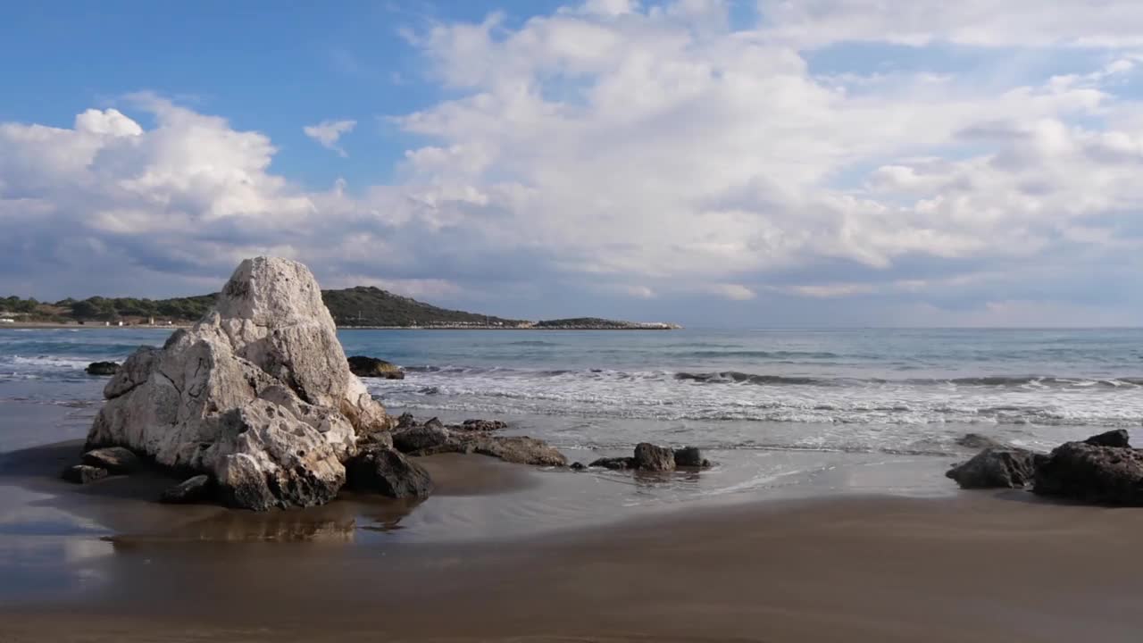 美丽的海景和岩石在一个晴天，多云的天空和平静的海浪视频素材