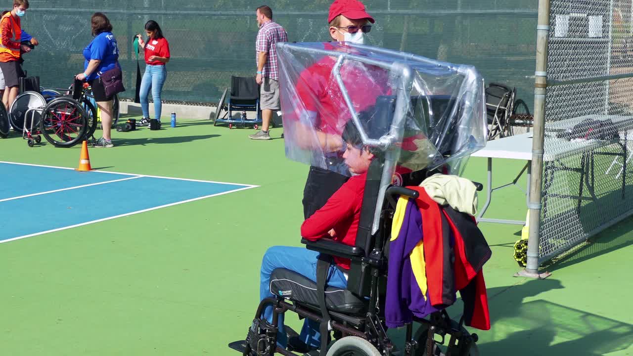 在帕萨迪纳，加利福尼亚州，4K体育比赛中，父亲在轮椅上喂他残疾的儿子视频下载