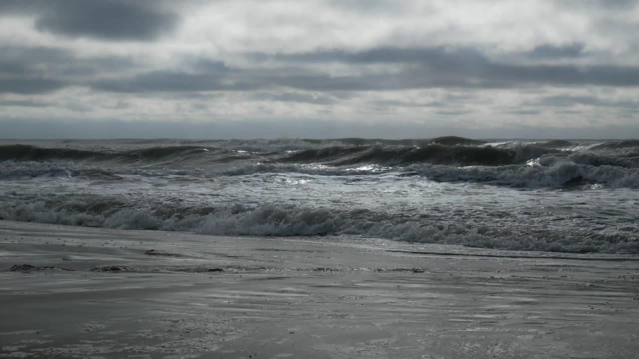 在多云的日子里，波涛汹涌的海面伴随着汹涌的海浪冲击着海岸线视频下载