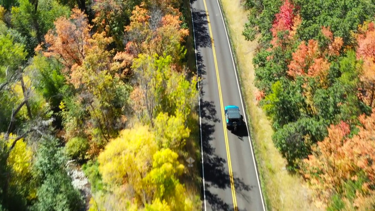无人机飞越山林路，跟踪路上的一辆蓝色汽车视频下载