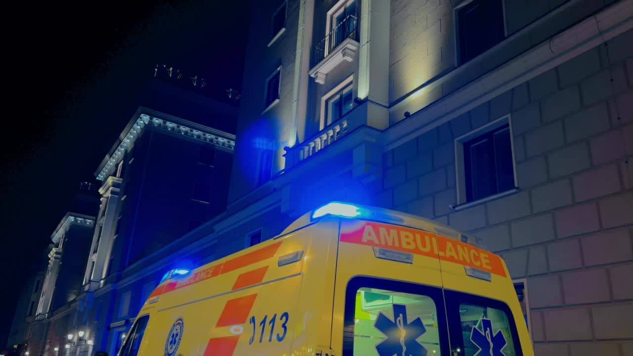 夜晚，救护车撞在巨大的酒店大楼上，警笛闪烁视频素材