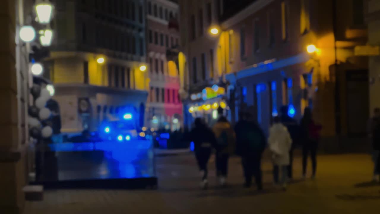 模糊:人们走在夜晚的城市，撞到一辆警笛闪烁的救护车视频素材