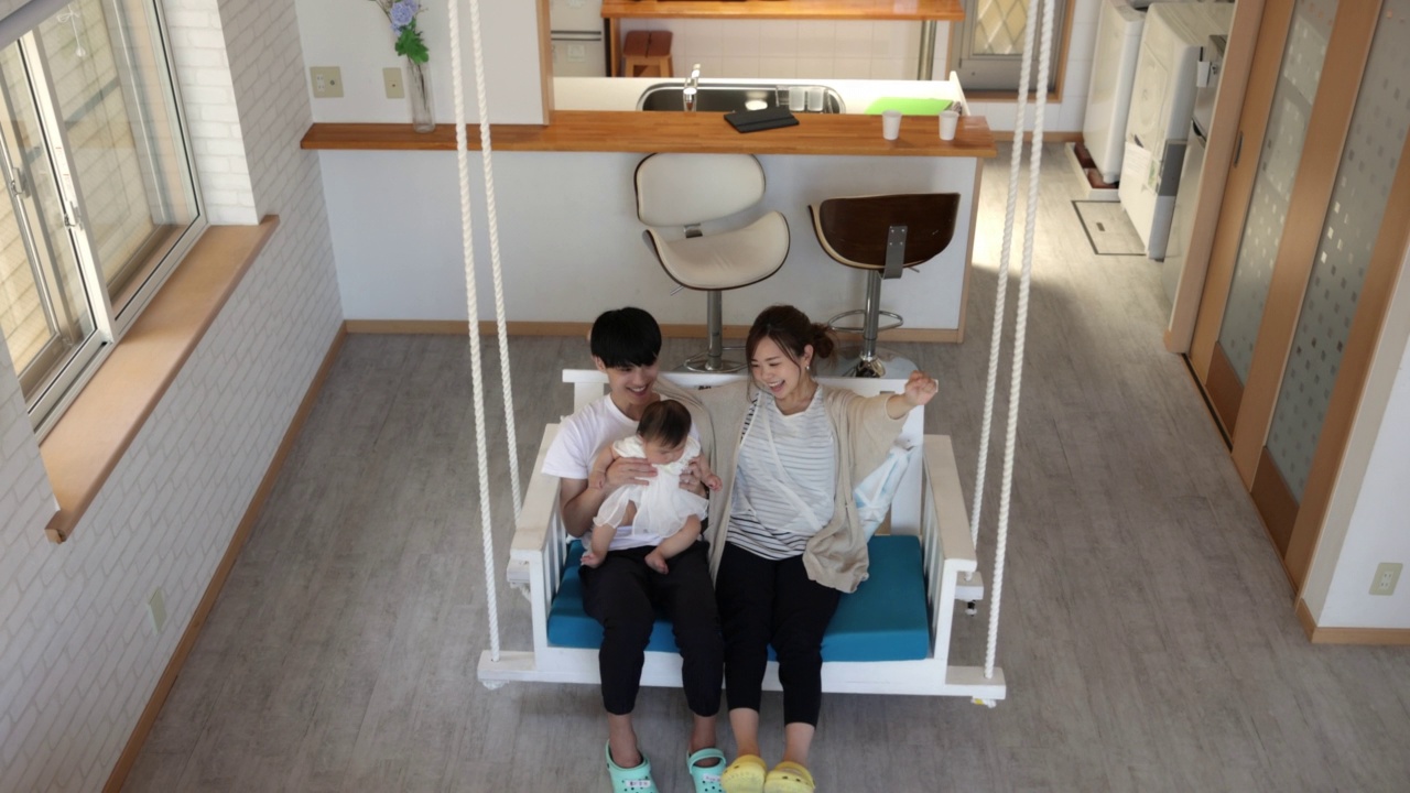 一家人一起坐在民宿酒店的秋千上-高角度的风景视频下载