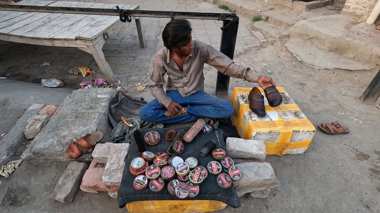 一个年轻的贫穷男孩在农村街头擦鞋赚钱。视频下载