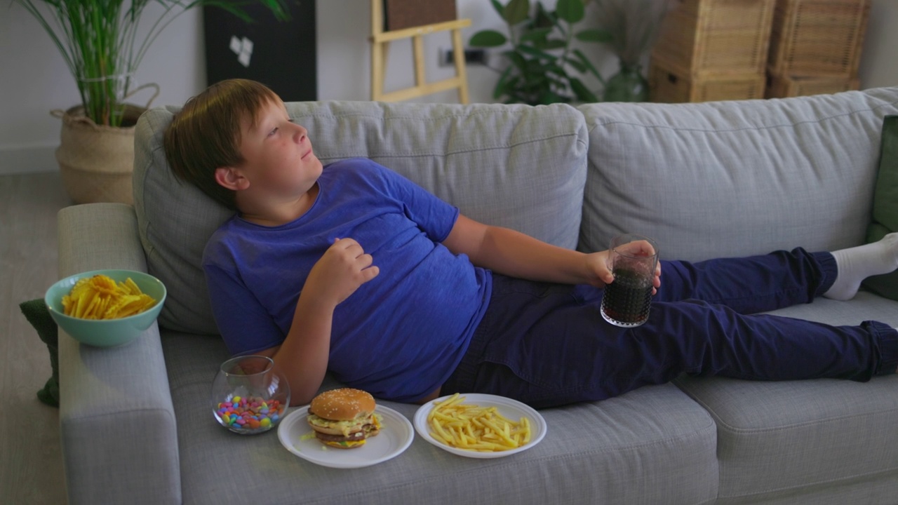 一个白人少年坐在家里吃不健康的食物视频素材