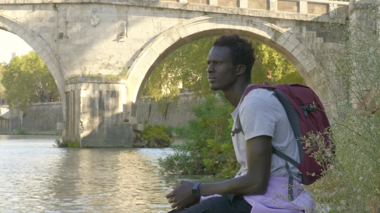 沉思的黑人环顾四周，在河岸上寻找答案视频素材