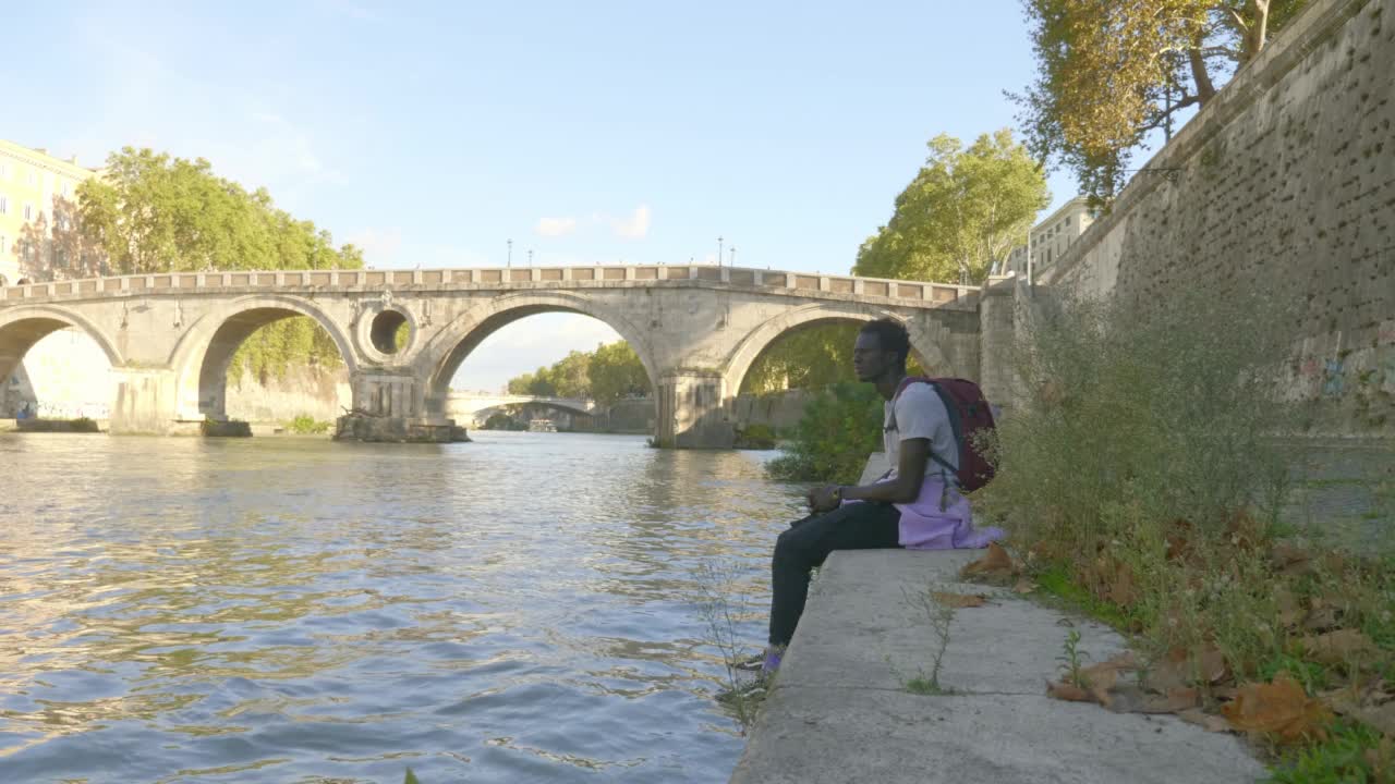 忧郁的概念:坐在河岸上的悲伤的非洲人视频素材