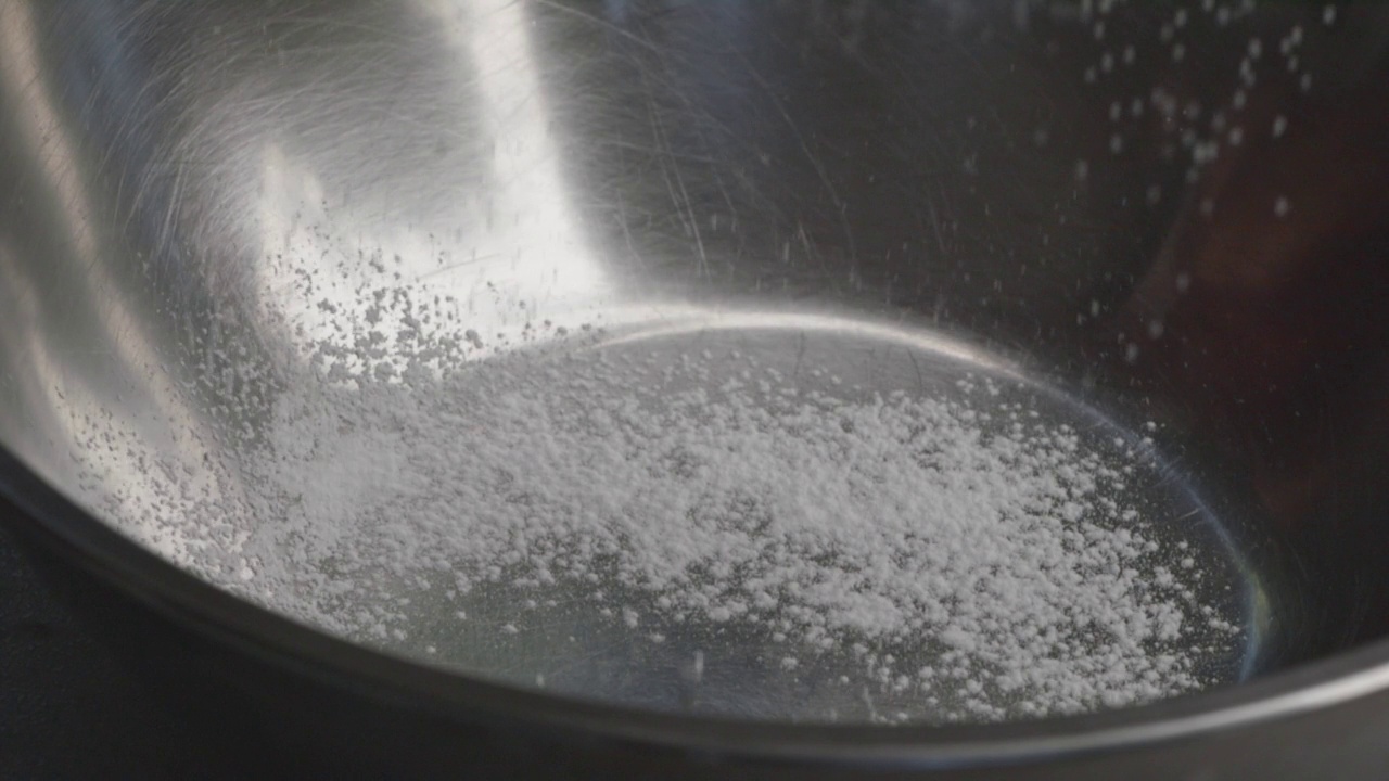 厨房里的面粉筛中落下的白色细面粉的特写镜头。,慢动作视频素材