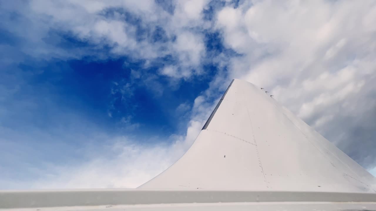 飞机尾部和白色机身表面的低角度平移视图。蓝天为背景视频下载