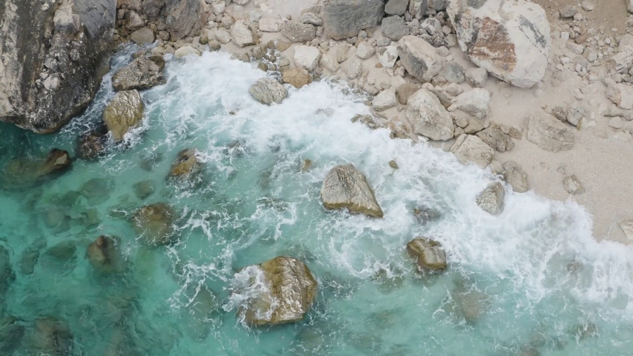 从上到下的岩石海岸与温和的波浪翻滚鸟瞰夏季海景视频下载