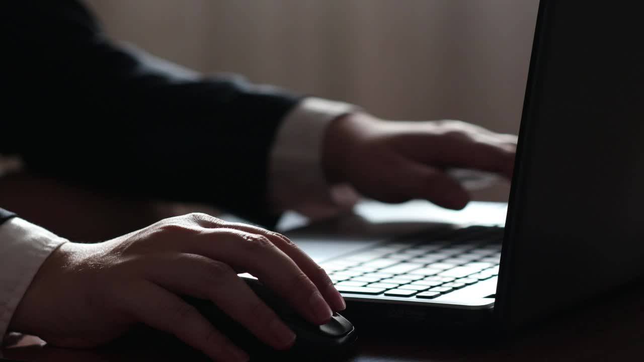 一位商人的手坐在家里的办公桌上，在笔记本电脑键盘上打字视频素材