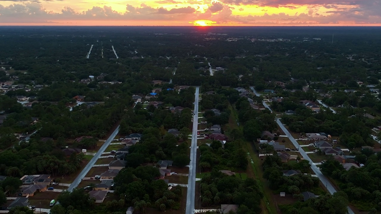 日落时分，佛罗里达州安静的乡村地区，绿色棕榈树之间的郊区私人住宅的鸟瞰图视频素材
