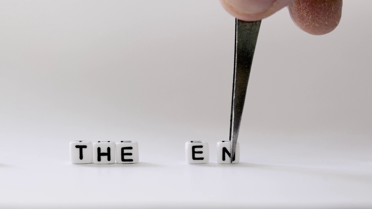 用镊子用手在白色背景上一个字母一个字母地显示“结束”视频下载
