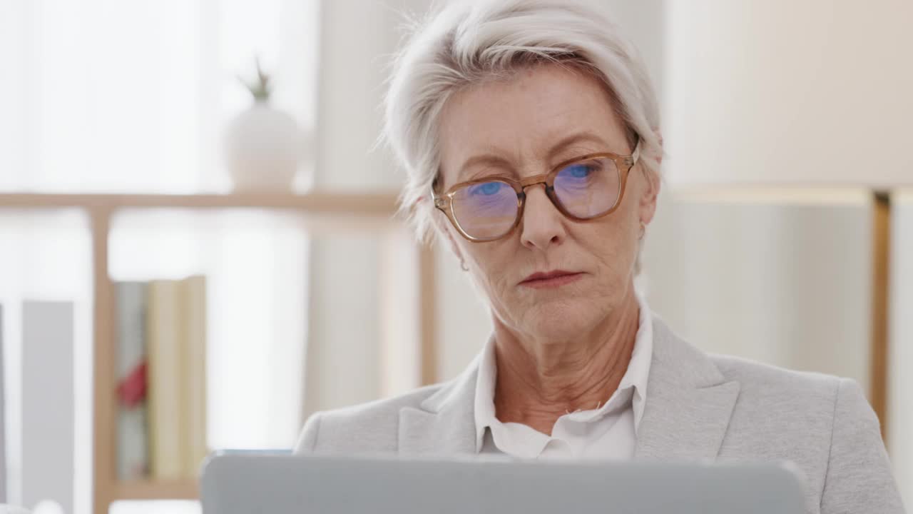画像老年自信，专业和快乐的女商人微笑着在笔记本电脑上工作。上了年纪的高级执行经理在工作中感到雄心勃勃，并希望在办公室取得成功。视频素材