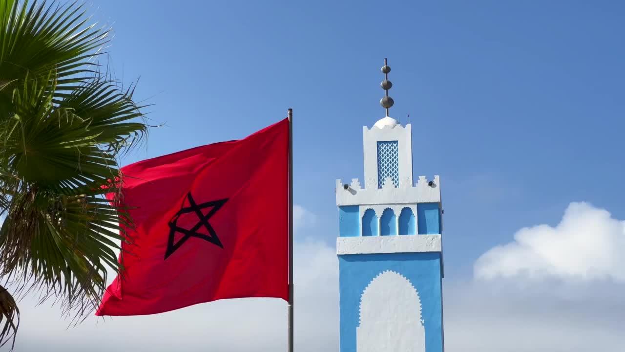 蓝白相间的清真寺尖塔上飘扬着摩洛哥国旗视频下载