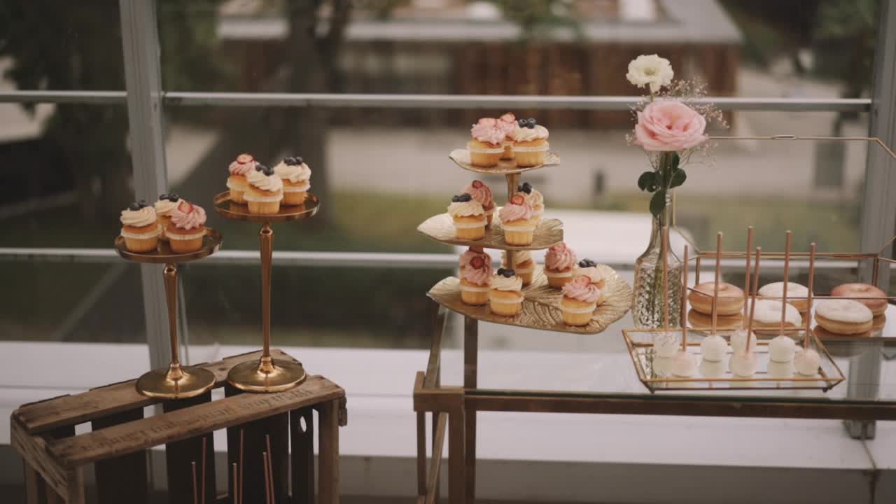婚礼派对的桌子在柔和的颜色纸杯蛋糕，甜甜圈花，相机从左到右移动视频素材
