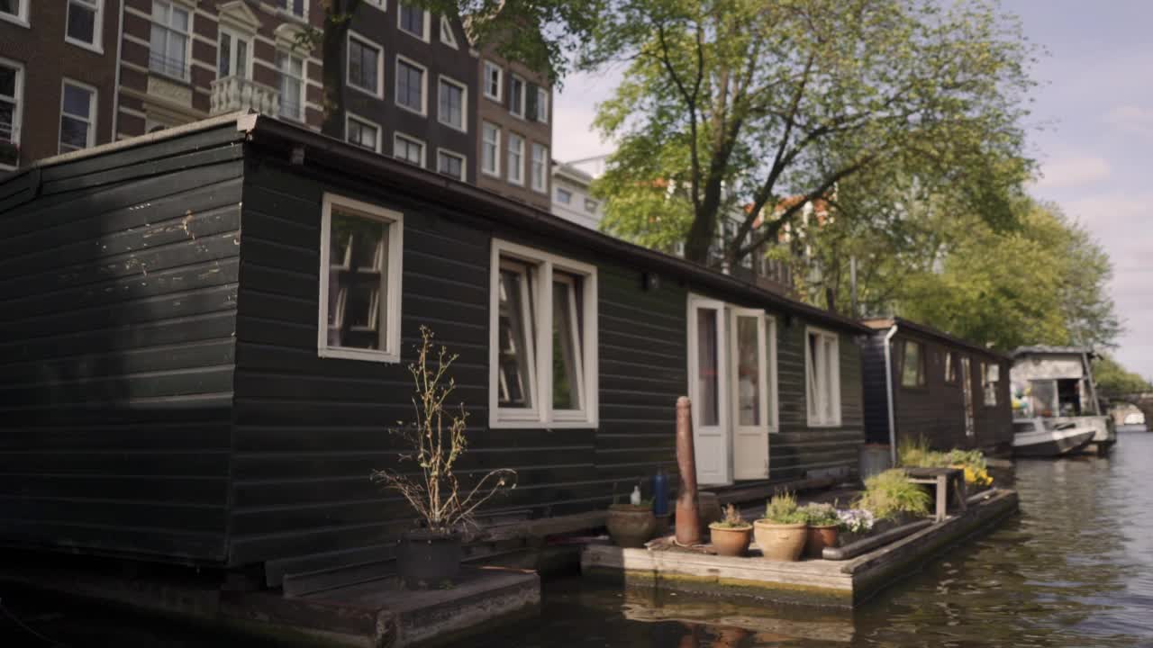 荷兰阿姆斯特丹漂浮的房屋的慢动作，背景是树木和建筑视频下载