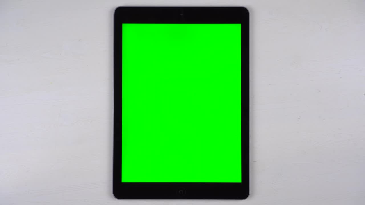 一个男人用手指轻敲桌子上平板电脑的屏幕。一个男人正在使用一个绿色屏幕的平板电脑。从以上观点。4 k视频下载