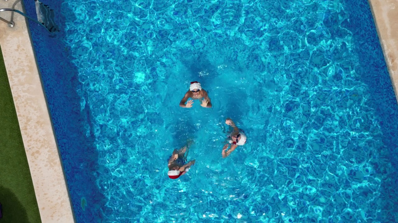 无人机拍摄的青少年在夏季圣诞节在游泳池游泳的画面视频下载