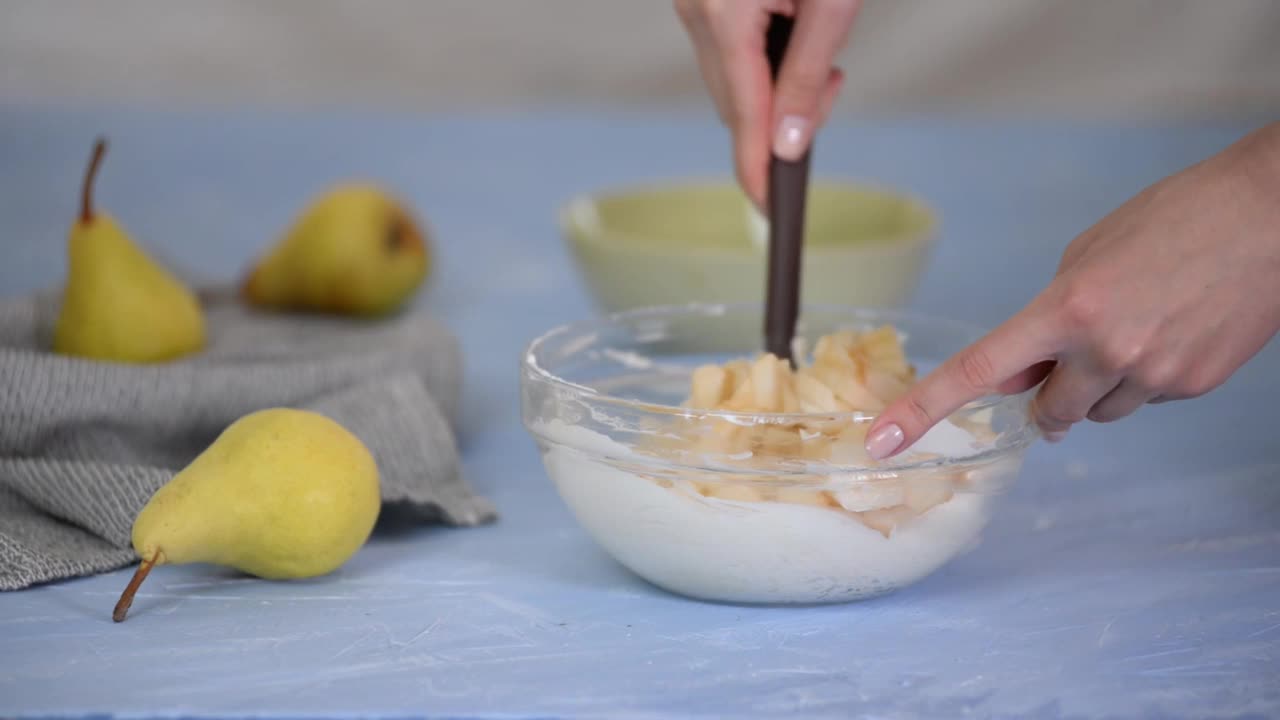 女性用手搅拌奶油奶酪和梨片。视频下载